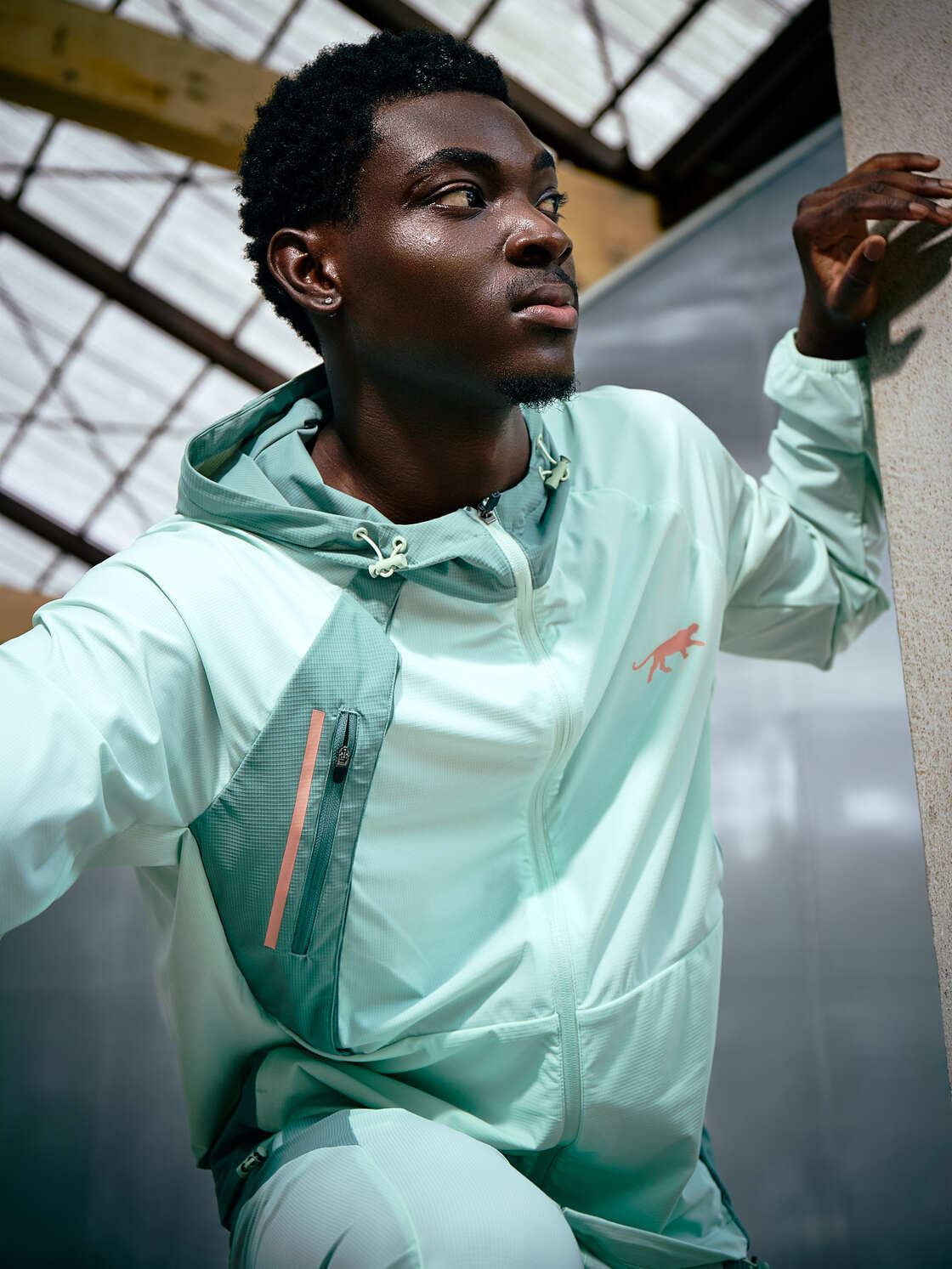 un homme penché en avant porte la veste de survêtement isandro Airness de couleur vert d'eau
