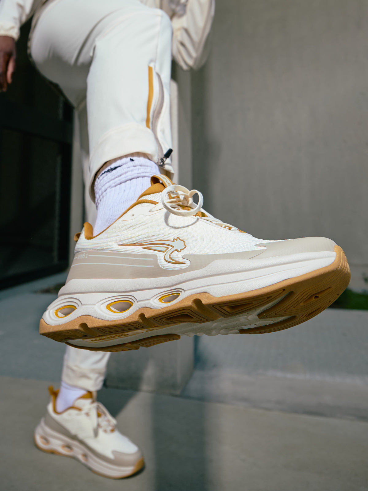 Sneakers Namib sable aux pieds d'un homme en survêtement Airness
